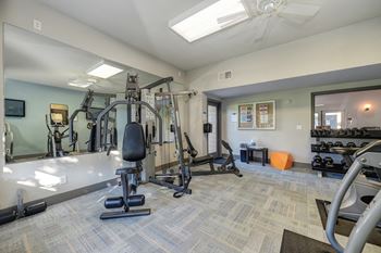 Community Fitness Center.  The Room has a light blue accent wall and contains a weight system, elliptical machines, bench and free weights.at Fountains of Fair Oaks, Fair Oaks